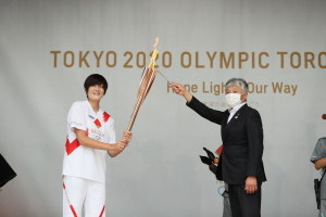 国立市で走る予定だったソフトボール女子金メダリスト、佐藤理恵さんのトーチに火を灯す永見市長。